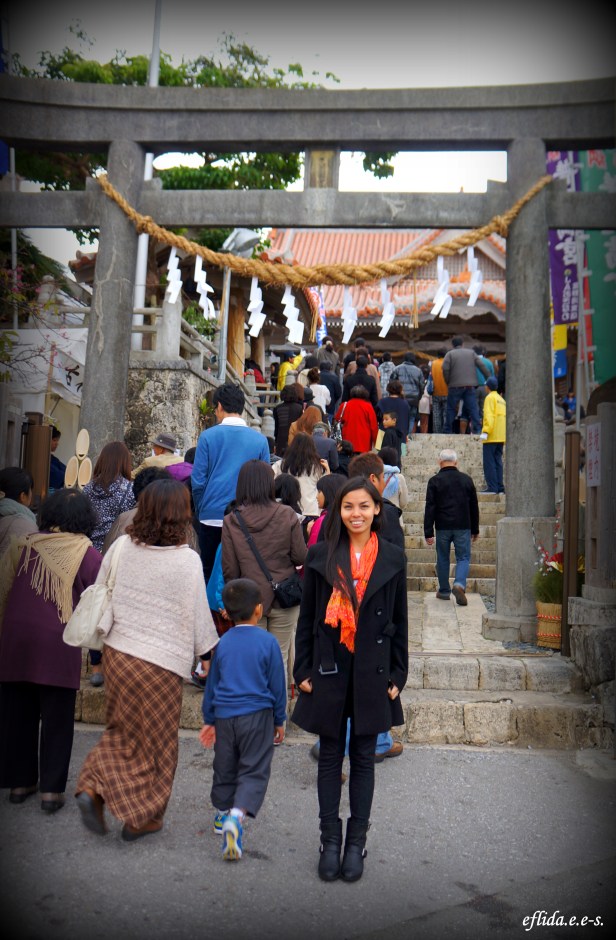 Passing under a torii, the traditional arched gateway to a Shinto shrine, during Hatsumode in Futenma Shrine, Ginowan in Okinawa, Japan. Passing under a torii, the traditional arched gateway to a Shinto shrine, during Hatsumode in Futenma Shrine, Ginowan in Okinawa, Japan.