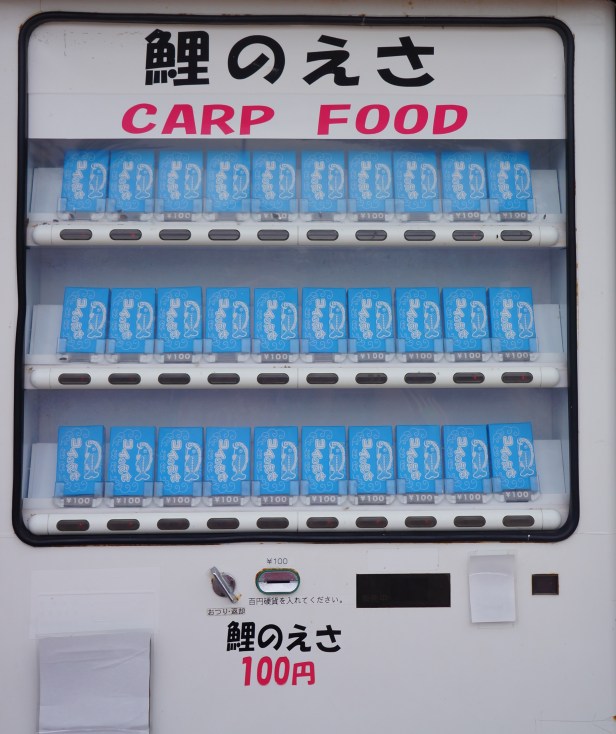 Fish food in boxes are available on a vending machine at 100 yen for koi and carp feeding at the Water Park in Southeast Botanical Garden in Okinawa City, Okinawa, Japan. (東南植物楽園 Tōnan Shokubutsu Rakuen)